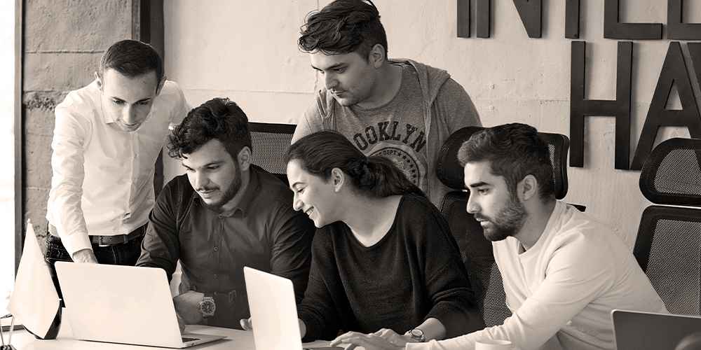 Office team discussing ideas around laptops